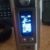 A small handheld device with a glowing blue display, resting beside a radio.